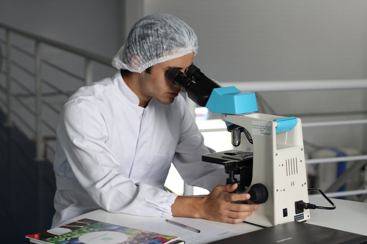 Scientist in a lab coat using a microscope to conduct research, focusing on healthcare improvements. — driveway sealer and coating